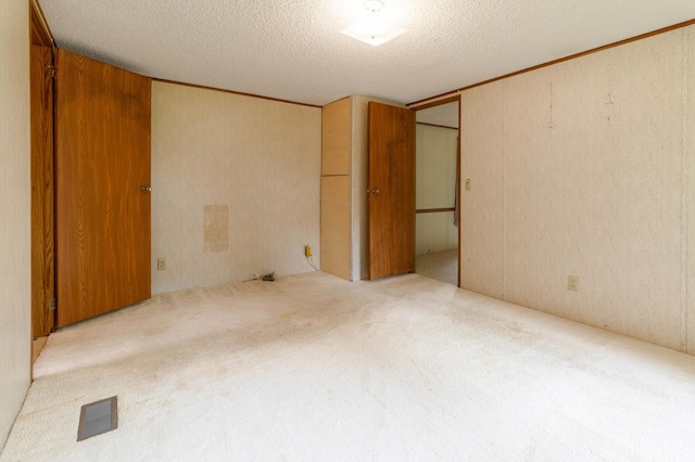 unfurnished bedroom featuring a textured ceiling, light colored carpet, and a closet