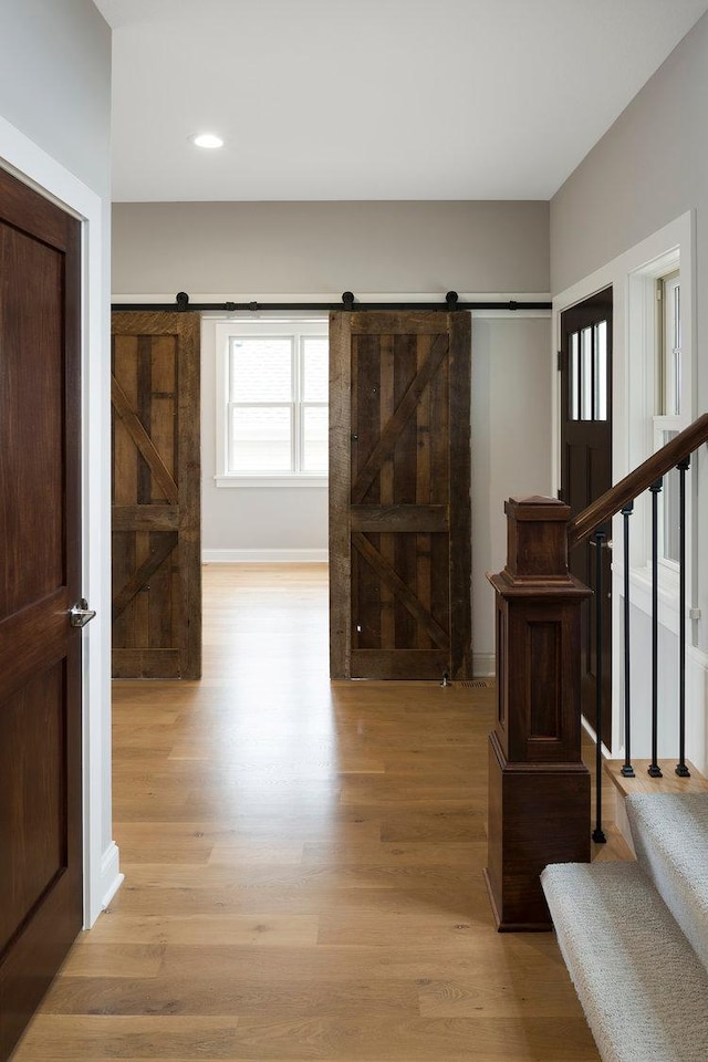 foyer entrance with a barn door and light wood-type flooring