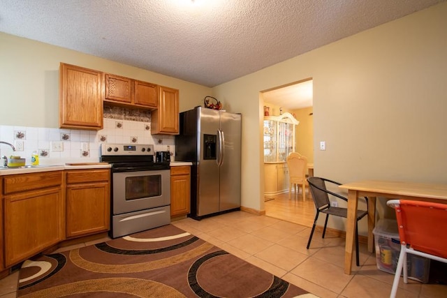 kitchen featuring backsplash, stainless steel appliances, sink, light tile patterned flooring, and a textured ceiling