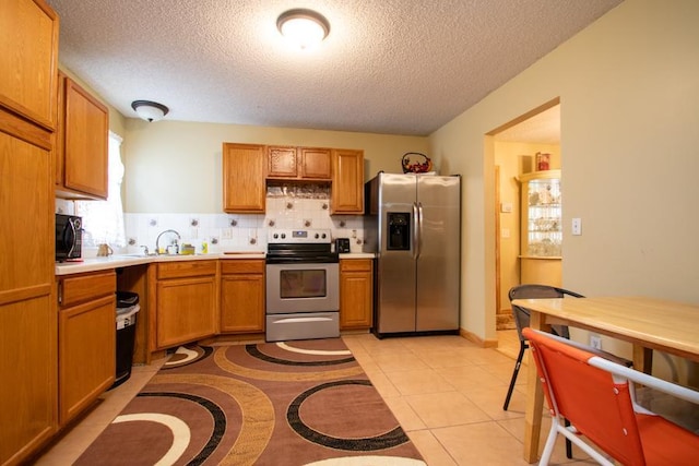 kitchen with appliances with stainless steel finishes, tasteful backsplash, plenty of natural light, and light tile patterned floors