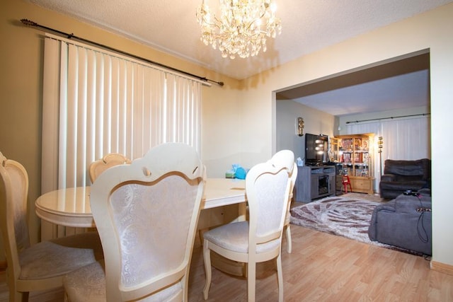 dining space with light hardwood / wood-style flooring and a notable chandelier