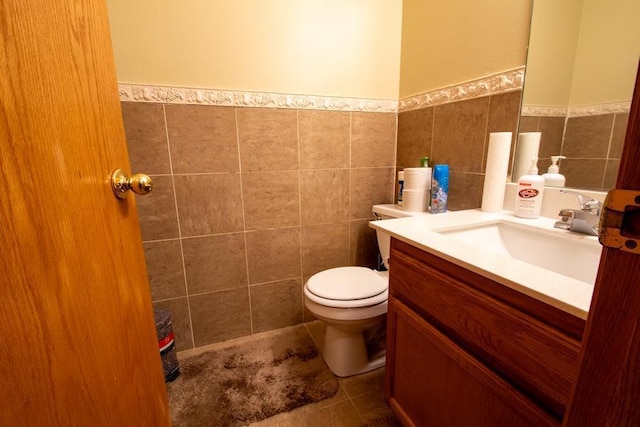 bathroom with tile walls, toilet, vanity, and tile patterned floors