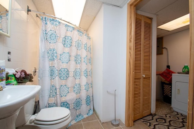 bathroom with toilet, walk in shower, tile patterned floors, electric panel, and washer / clothes dryer