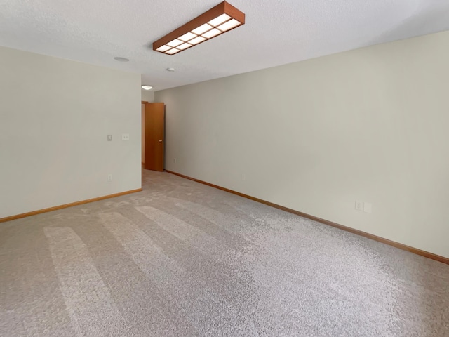 spare room featuring a textured ceiling and light colored carpet