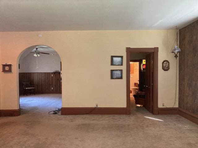 spare room with a ceiling fan, carpet, and arched walkways