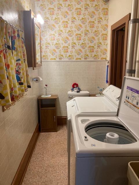 laundry room featuring a wainscoted wall, washer and clothes dryer, laundry area, and wallpapered walls