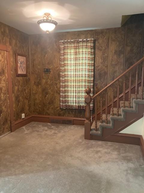 interior space featuring stairway, wood walls, and carpet floors