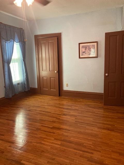 empty room featuring ceiling fan, baseboards, and wood finished floors