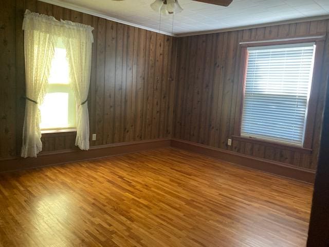 empty room featuring wood finished floors, a ceiling fan, and ornamental molding