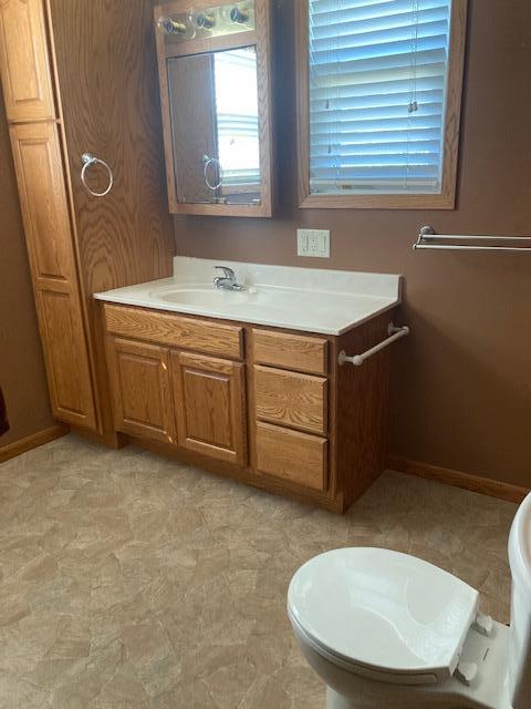 bathroom with baseboards, toilet, and vanity