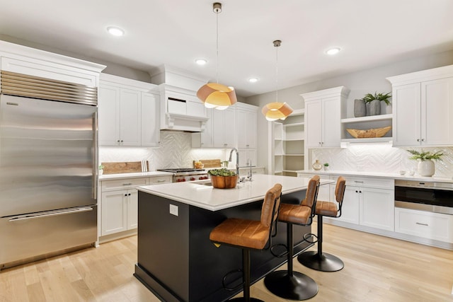 kitchen with premium range hood, open shelves, a sink, light countertops, and built in refrigerator