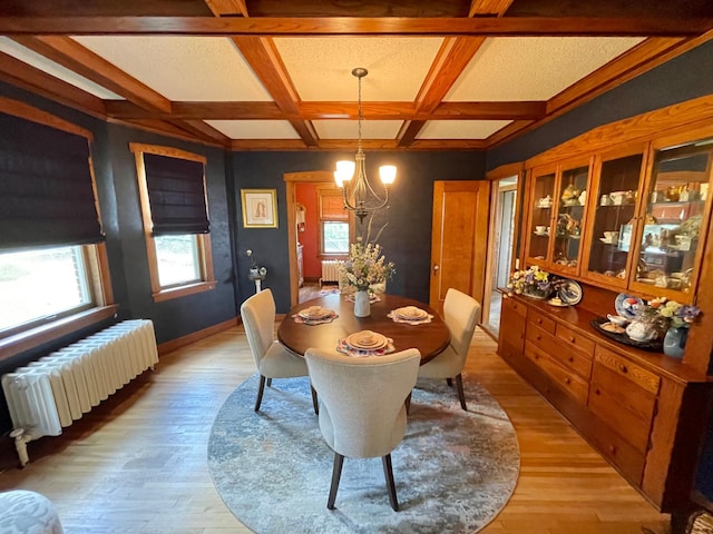 dining room featuring coffered ceiling, light hardwood / wood-style flooring, beam ceiling, and radiator heating unit