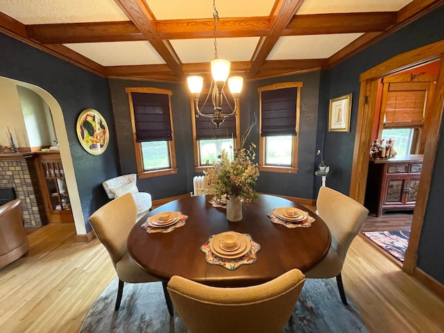 dining space with a healthy amount of sunlight, coffered ceiling, and light hardwood / wood-style flooring