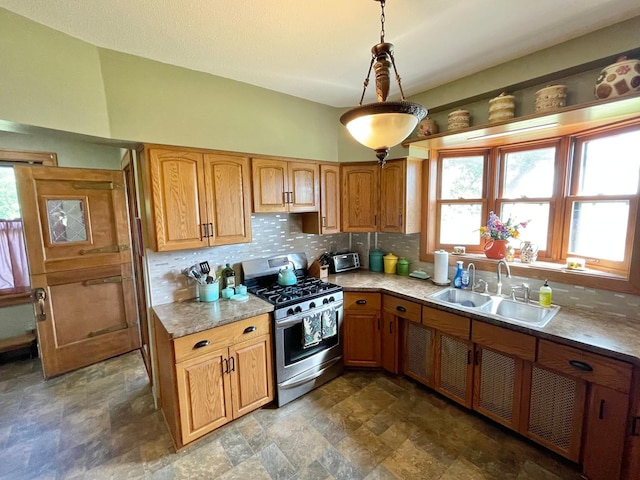 kitchen with stainless steel gas range oven, decorative light fixtures, sink, and tasteful backsplash