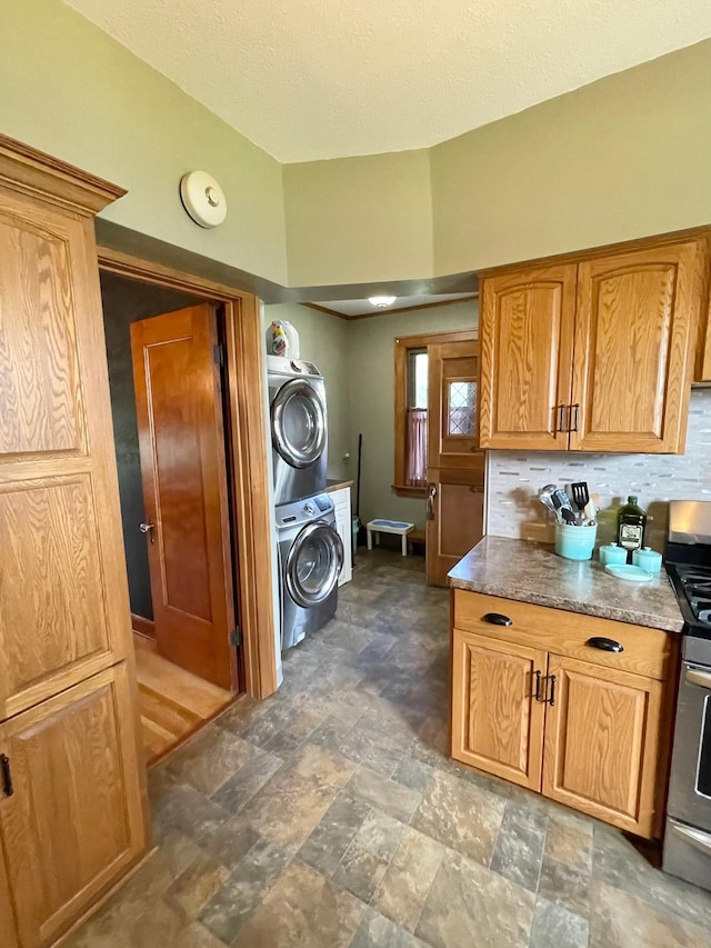 laundry area with a textured ceiling and stacked washer and clothes dryer