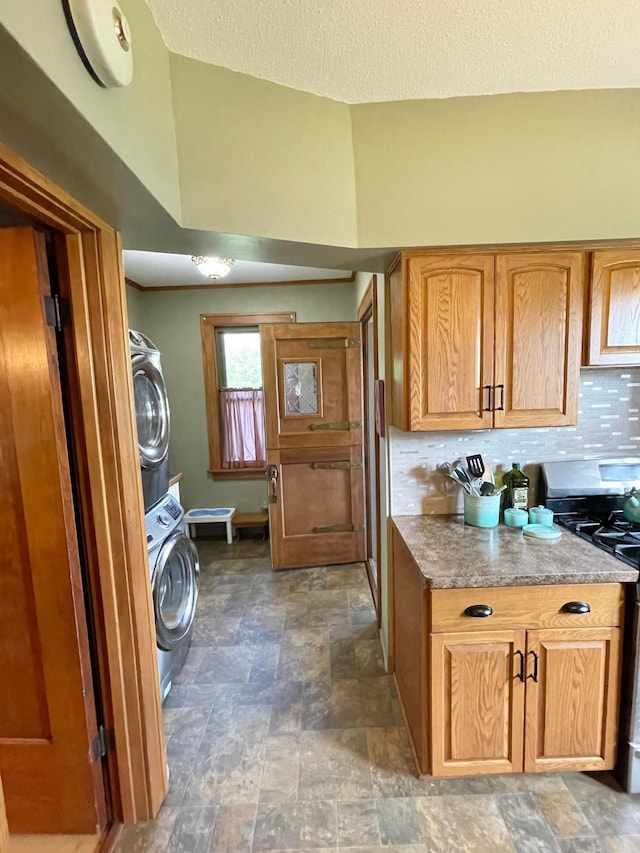 laundry room featuring a textured ceiling and stacked washer / drying machine