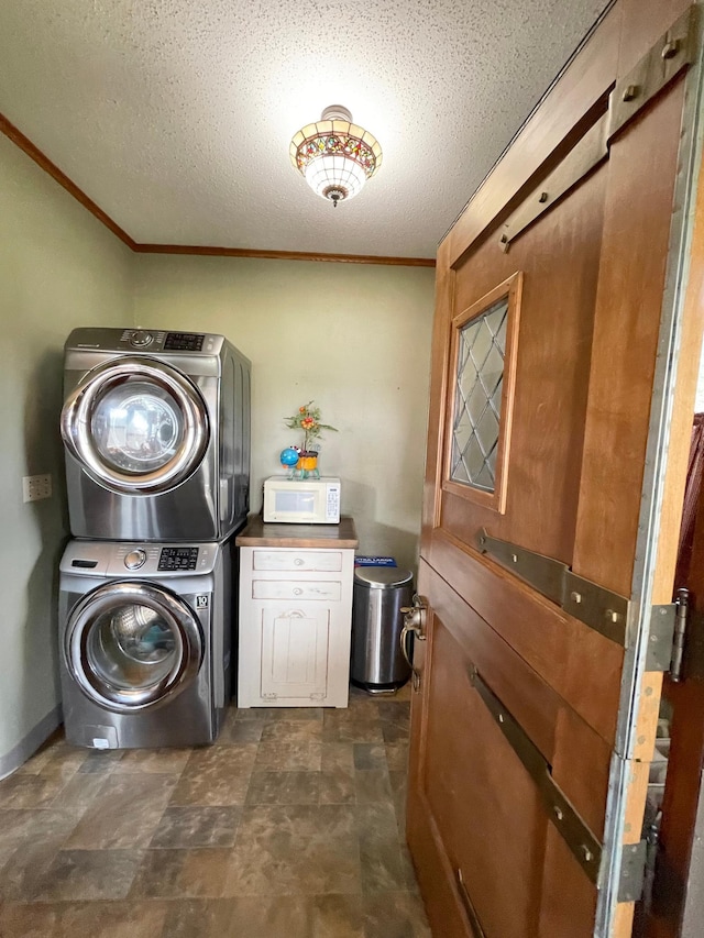 clothes washing area featuring cabinets, stacked washer and dryer, a textured ceiling, and ornamental molding