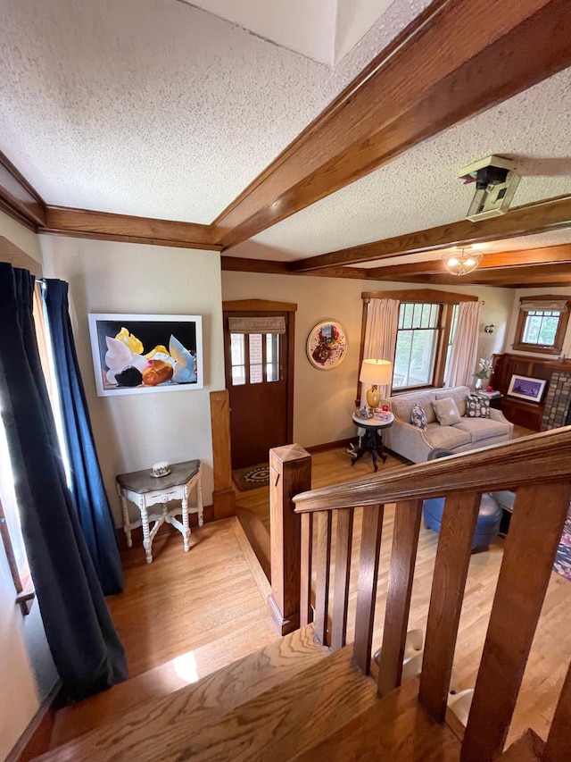 interior space featuring a textured ceiling, beam ceiling, and hardwood / wood-style floors