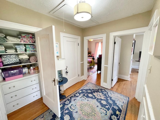 hall featuring a textured ceiling and light hardwood / wood-style flooring