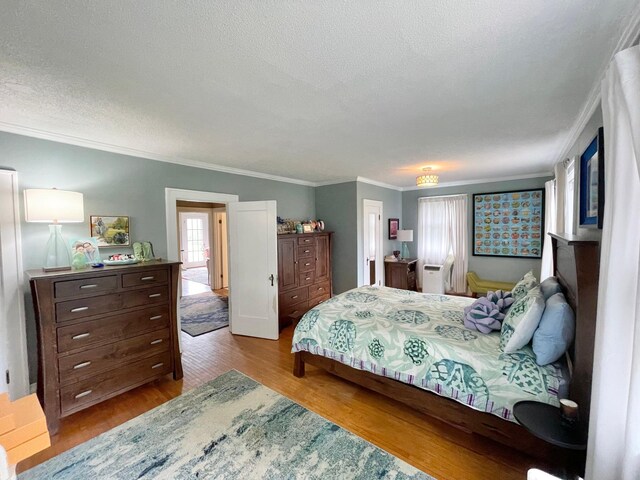 bedroom with a textured ceiling, ornamental molding, and light hardwood / wood-style flooring