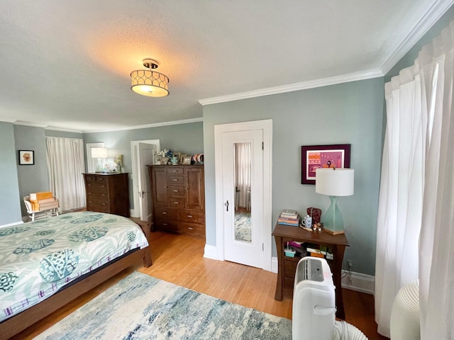 bedroom featuring light hardwood / wood-style flooring, a textured ceiling, and crown molding