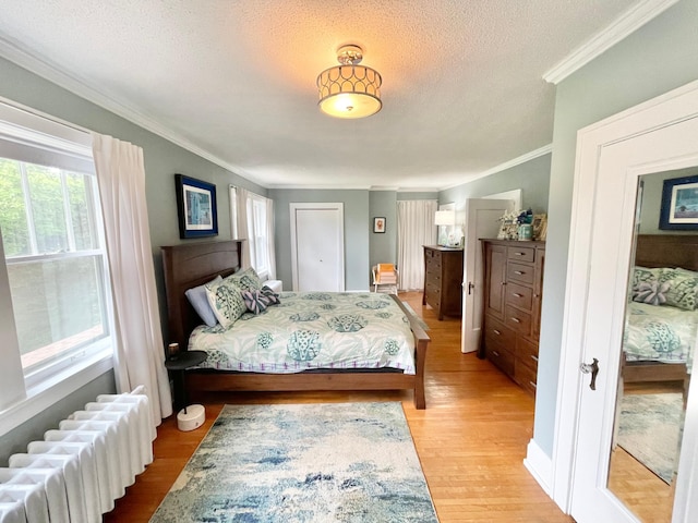 bedroom with ornamental molding, radiator, a textured ceiling, and light wood-type flooring