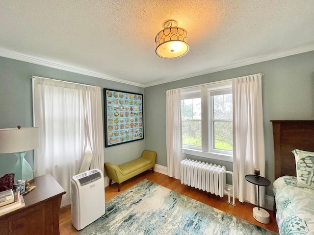 living area with radiator, ornamental molding, hardwood / wood-style floors, and a textured ceiling