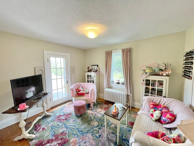 living room featuring a textured ceiling, a healthy amount of sunlight, radiator, and hardwood / wood-style flooring