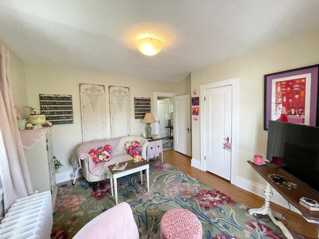 living room featuring radiator heating unit, a textured ceiling, and dark hardwood / wood-style flooring