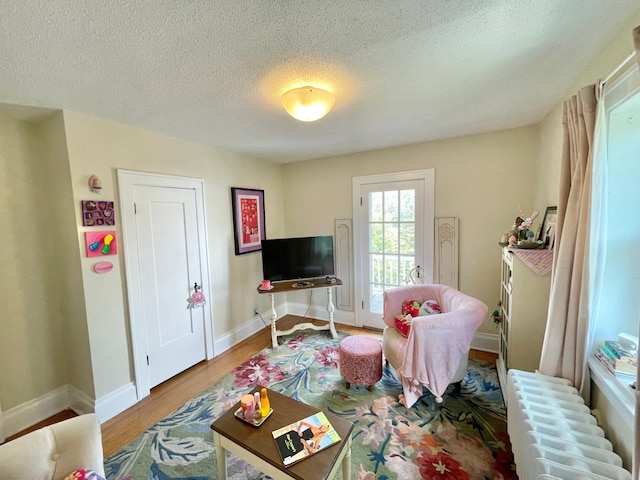 playroom featuring a textured ceiling, light hardwood / wood-style floors, and radiator heating unit