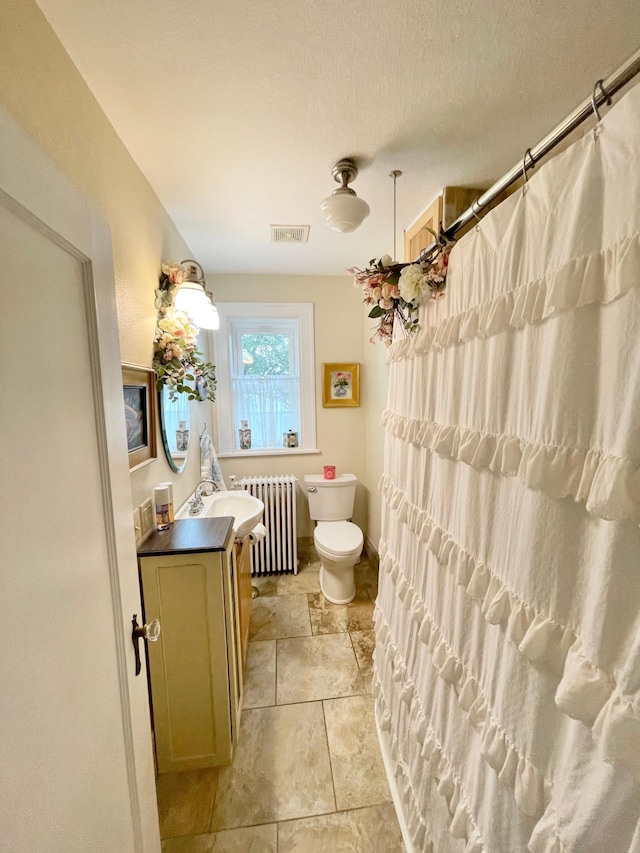 bathroom featuring radiator, vanity, toilet, a textured ceiling, and tile patterned flooring