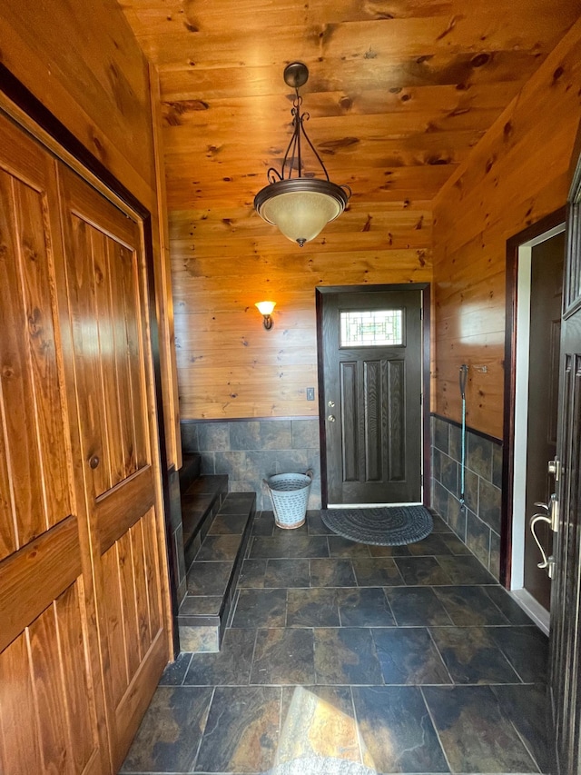 foyer featuring wood ceiling and wood walls