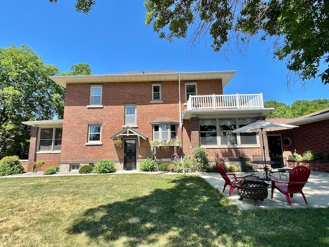 rear view of house with a lawn, a balcony, a patio area, and an outdoor fire pit