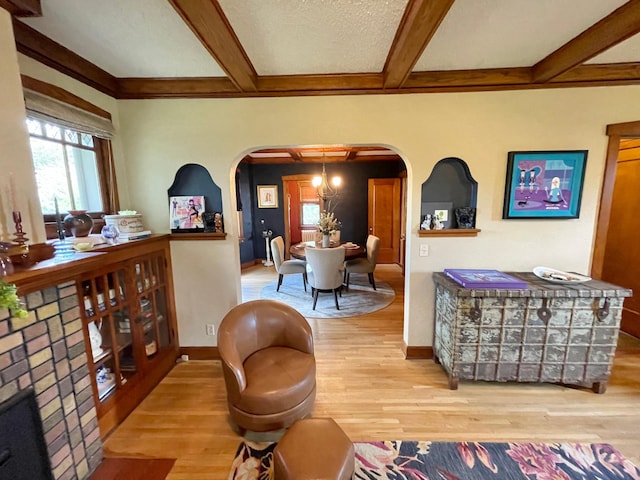 living room with a textured ceiling, hardwood / wood-style floors, beamed ceiling, and a notable chandelier