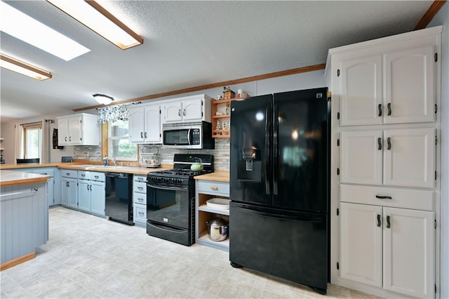 kitchen with black appliances, ornamental molding, wooden counters, and white cabinets