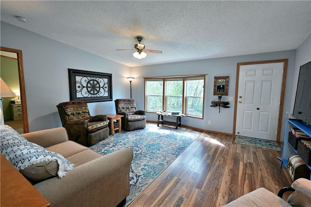 living room featuring ceiling fan, dark wood-type flooring, and a textured ceiling