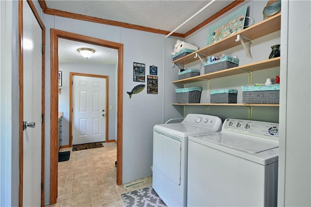 laundry room with washer and clothes dryer, a textured ceiling, and ornamental molding