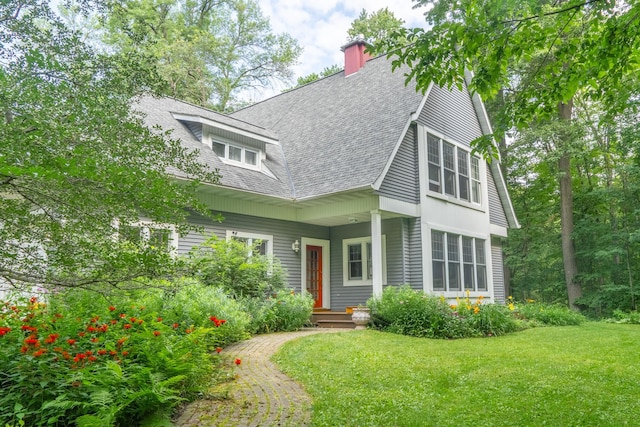 view of front of house with a chimney, a front lawn, and a shingled roof