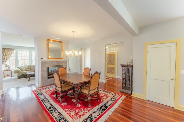 dining room featuring a chandelier, baseboards, wood finished floors, and a tile fireplace