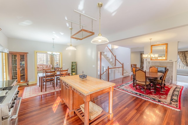 dining room featuring a wealth of natural light, a notable chandelier, wood finished floors, and stairs