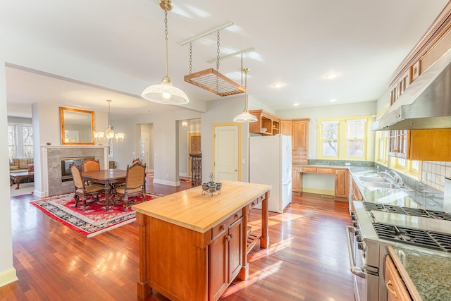 kitchen with wood finished floors, freestanding refrigerator, a sink, high end stove, and butcher block counters