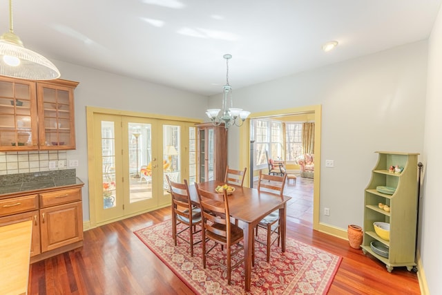 dining room featuring french doors, wood finished floors, baseboards, and a chandelier