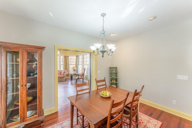 dining space with baseboards, wood finished floors, and a chandelier