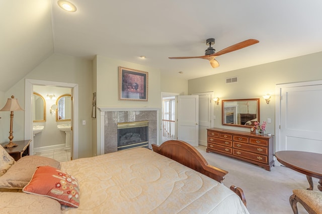 bedroom featuring a high end fireplace, visible vents, connected bathroom, ceiling fan, and light colored carpet