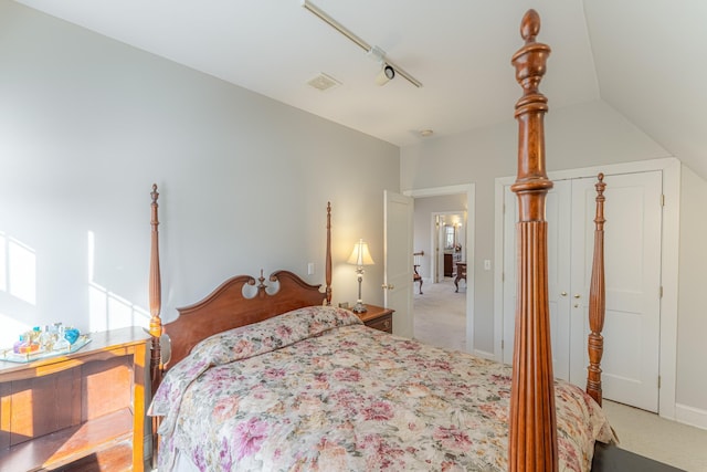 bedroom featuring visible vents, lofted ceiling, light colored carpet, and a closet