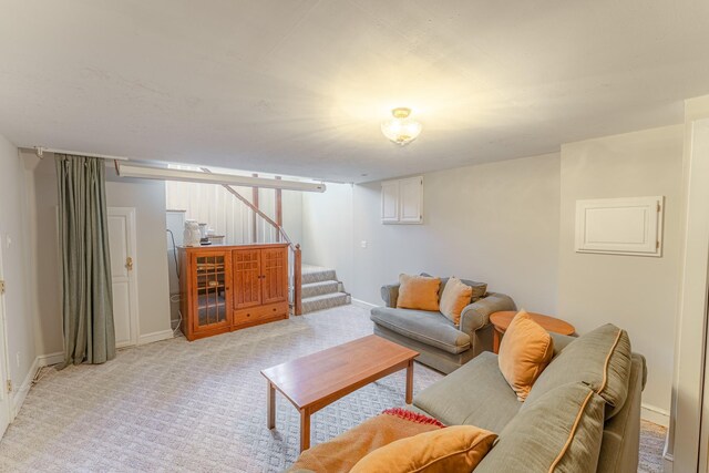 living room featuring stairway, baseboards, and light colored carpet