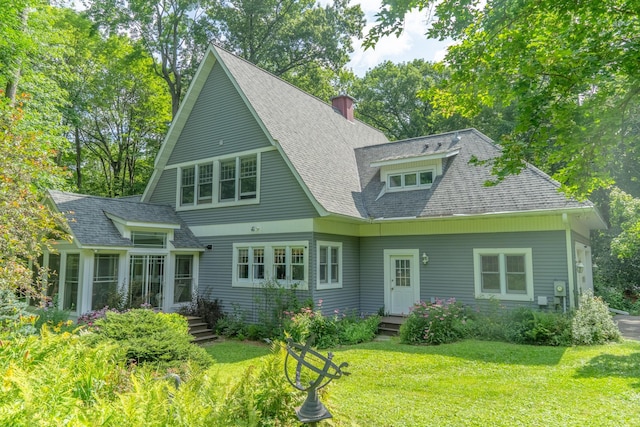 back of house featuring a yard, a shingled roof, a chimney, and a sunroom