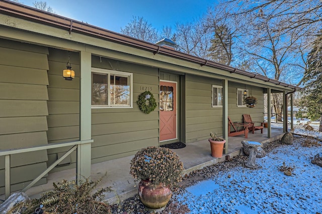 snow covered property entrance with a porch