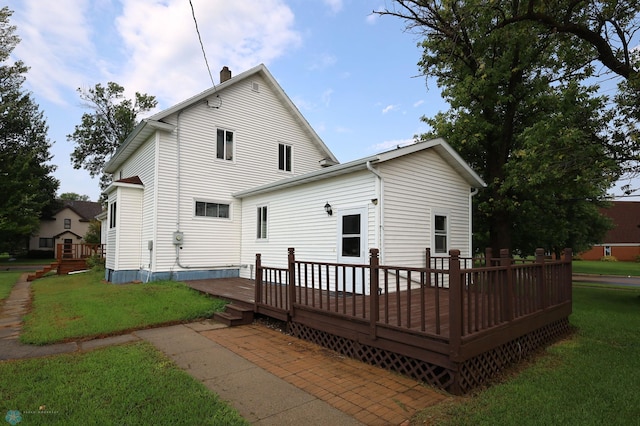 rear view of property featuring a deck, a yard, and a chimney