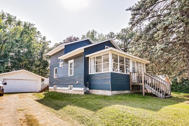 view of front of home featuring an outbuilding, a garage, a sunroom, and a front yard